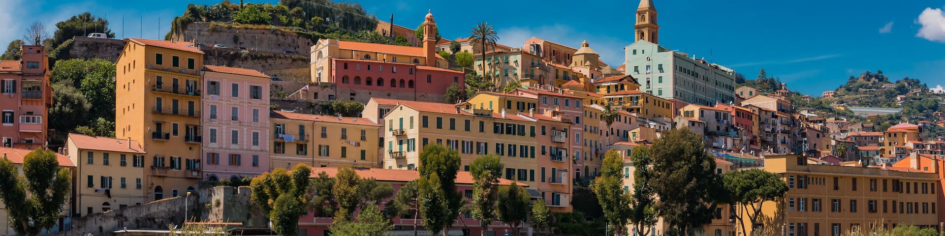 A coastal town with colorful buildings, a prominent church with a bell tower, and a cliff overlooking the sea.