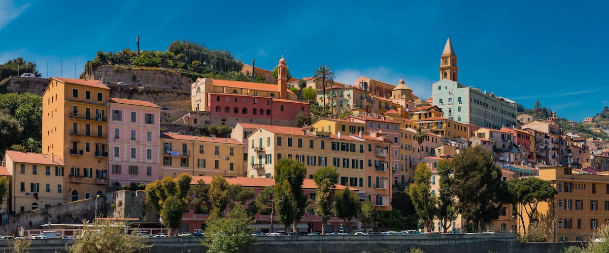 A coastal town with colorful buildings, a prominent church with a bell tower, and a cliff overlooking the sea.
