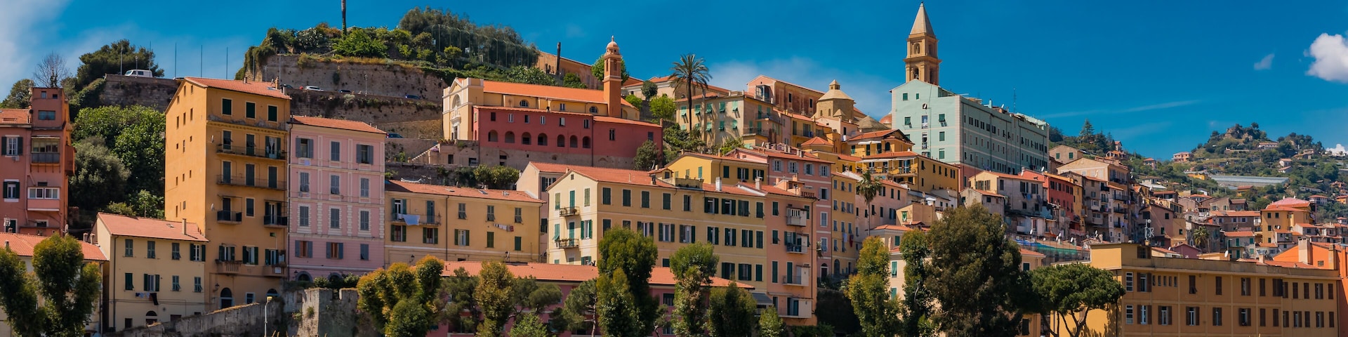 A coastal town with colorful buildings, a prominent church with a bell tower, and a cliff overlooking the sea.