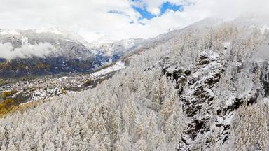Ein verschneites Gebirge mit einer Stadt im Tal darunter.