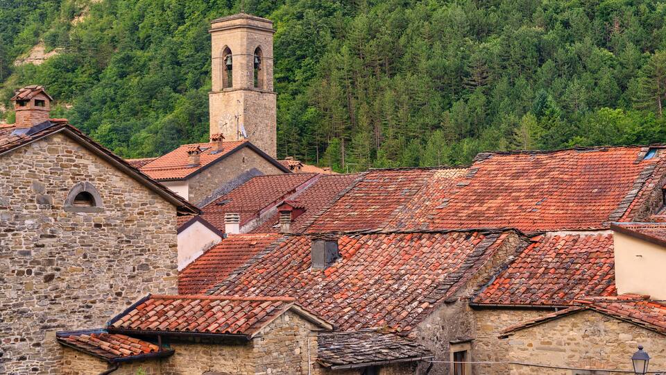A historic town with stone buildings, red-tiled roofs, and a bell tower.