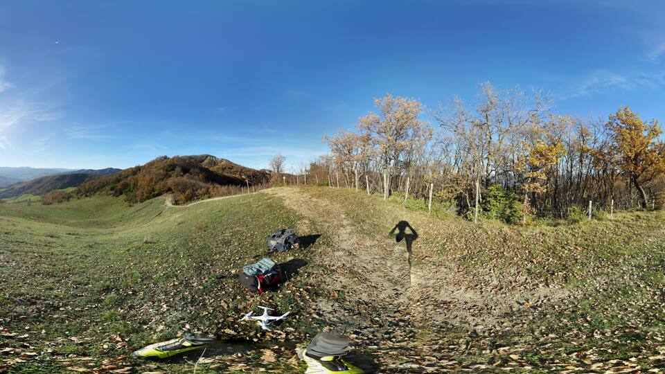 A hilly landscape with a dirt path, trees, and backpacks.