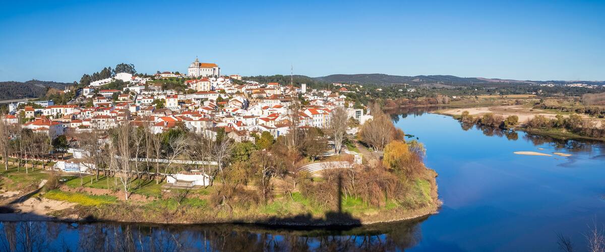 A town by a river with a prominent white church on a hill.