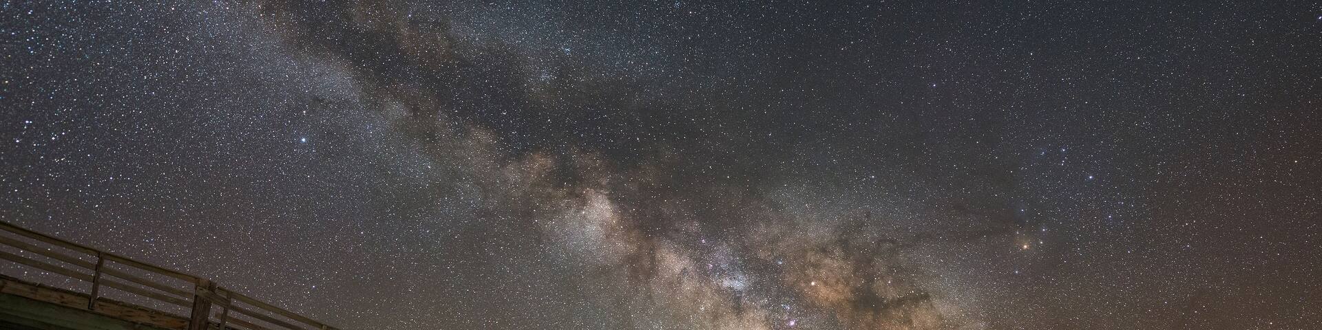 Mand exploring Frisco Pier damage under the Milky Way galaxy