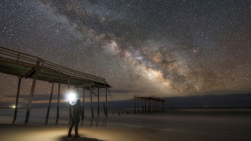Mand exploring Frisco Pier damage under the Milky Way galaxy