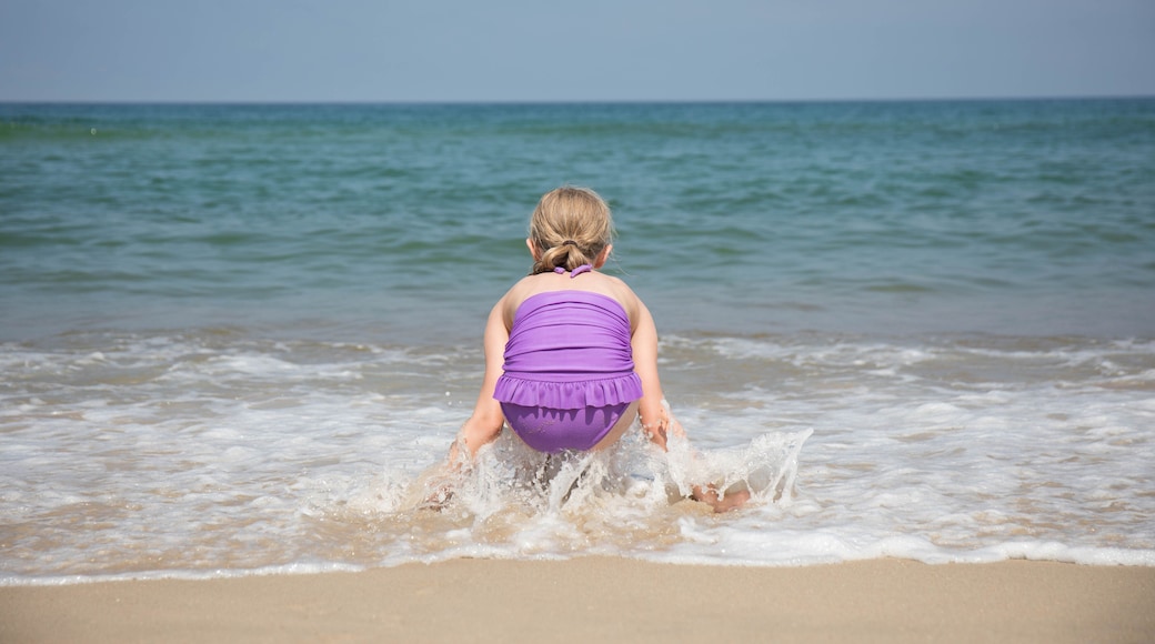 A 9 year old girl playing in the waves as they come ashore at the beach.
