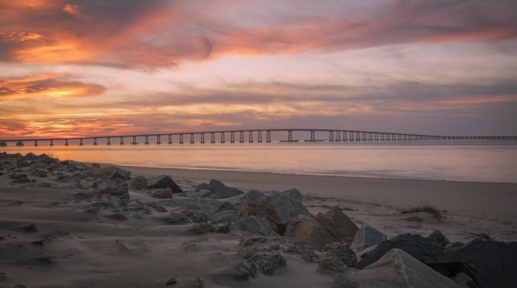 This image was captured at the Oregon Inlet on the NC Outerbanks in December of 2015. It features the iconic Bonner Bridge, one of the more famous bridges in North Carolina. This was an impromptu trip that I undertook hoping to catch a sight of Comet Catalina that was gracing our skies at the time. That trip turned out to be one of the best trips I have ever undertaken as I encountered perfect conditions for photography every single day over the 3 day period I was there.
This image is a blend of 2 images to bring out some detail in the foreground rocks. This composition appealed to me since the foreground rocks form a natural line to lead the viewer's eyes to the bridge and the clouds above. The clouds on this day were assuming various familiar shapes with the one captured here taking the shape of a bird in flight.
This particular stretch of the shoreline is very peaceful to walk along. Since it's an inlet, the waves are extremely calm unless it's windy. There are several sand dunes to the left of this image that ultimately would lead you to the proper coast and the ocean.
Update, 2020: This bridge is being dismantled and replaced with a newer bridge. Bonner Bridge has a lot of history tied to it and while it's sad to see it go, I feel fortunate to have captured part of this history personally.
Thank you for stopping by and for the support.
#sunset #nc #usa #bridge #obx #outerbanks #colorful #goldenhour #roadtrip #weekend #beach #beaches #bestof5 #nationalpark #bridges #lovemytown
#history #BeachBound