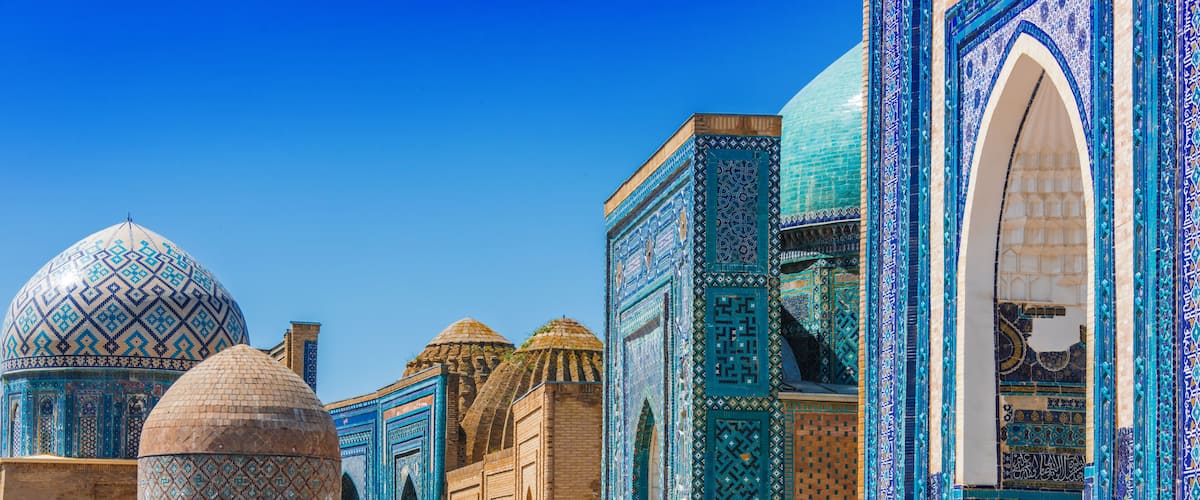 A mosque with blue and turquoise tile work, domes, and arched windows.