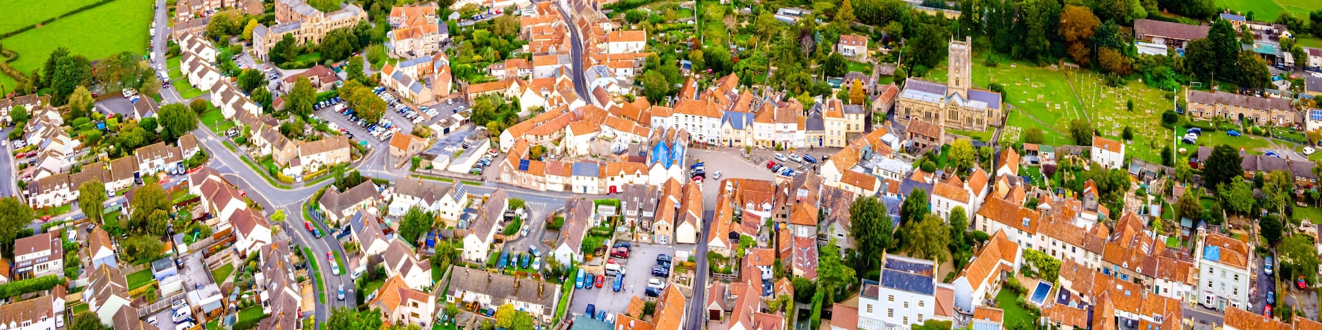 Uma cidade com uma igreja no centro, estradas sinuosas e campos verdes ao redor.