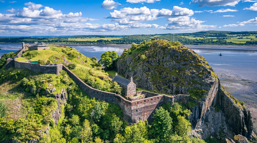 A historic fortification overlooking a river, surrounded by lush greenery and hills.