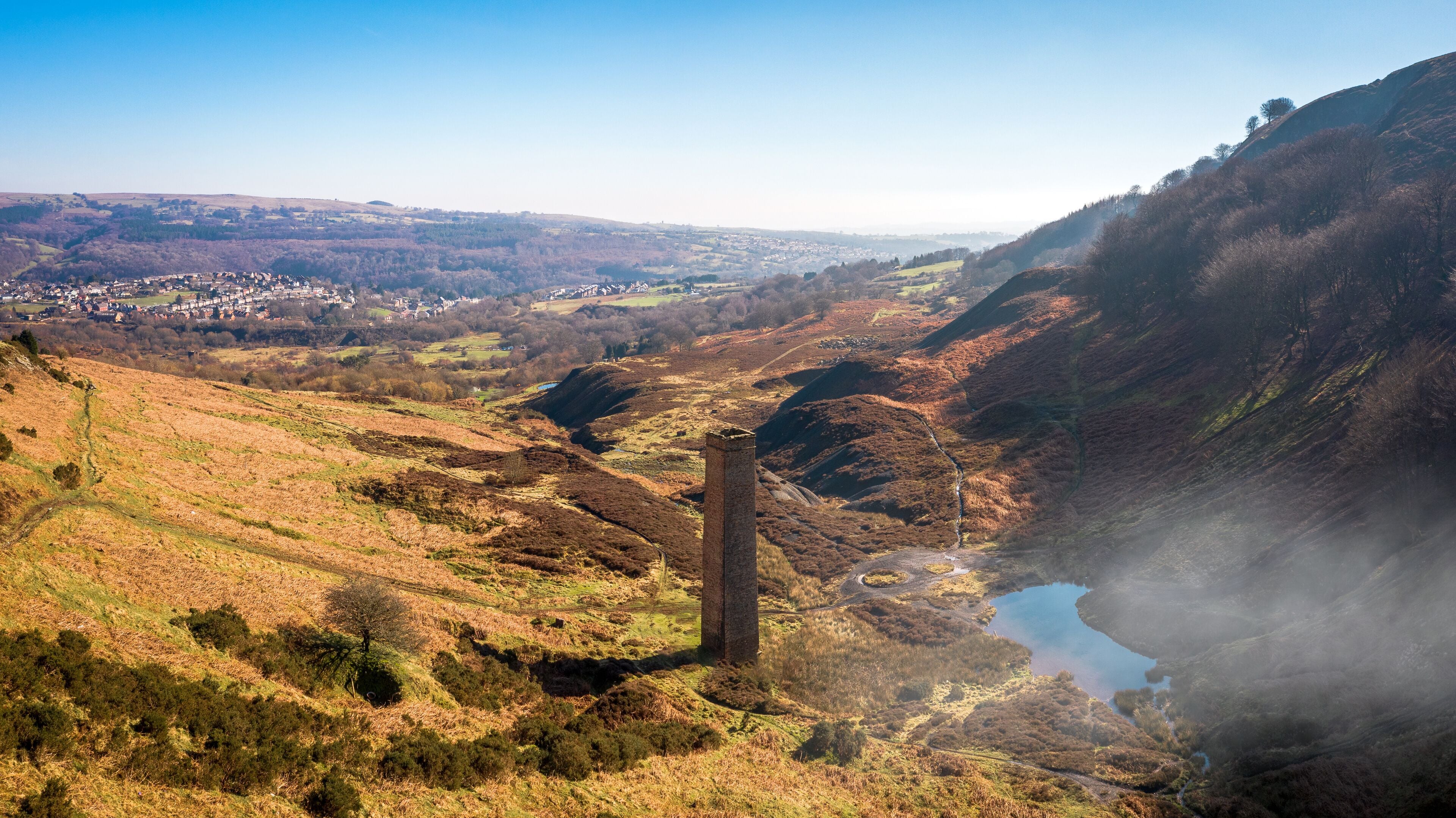 A valley with a river, a distant town, and a prominent stone tower.