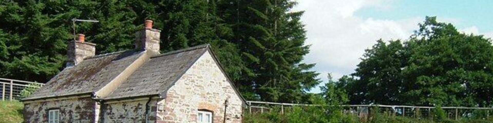 A stone house with a wooden fence, a stone bridge, and a tunnel entrance.