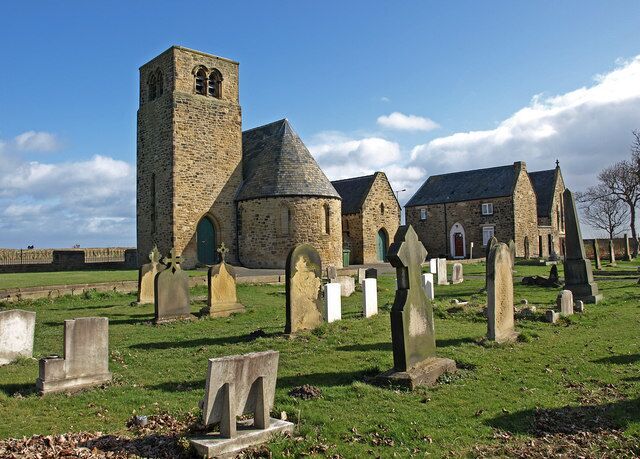 A historic church with a prominent tower and multiple tombs in a cemetery.