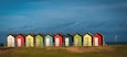 Blyth beach huts viewed from the road side, bathed in late afternoon sunshine.
