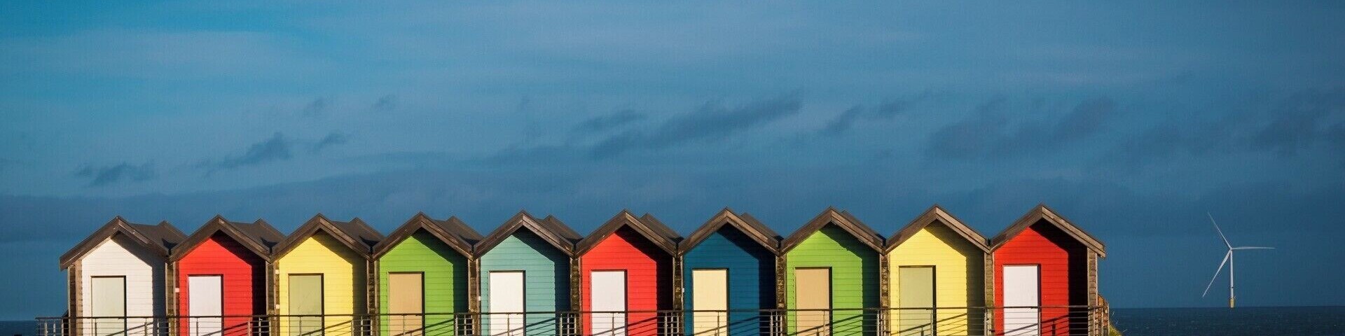 Blyth beach huts viewed from the road side, bathed in late afternoon sunshine.