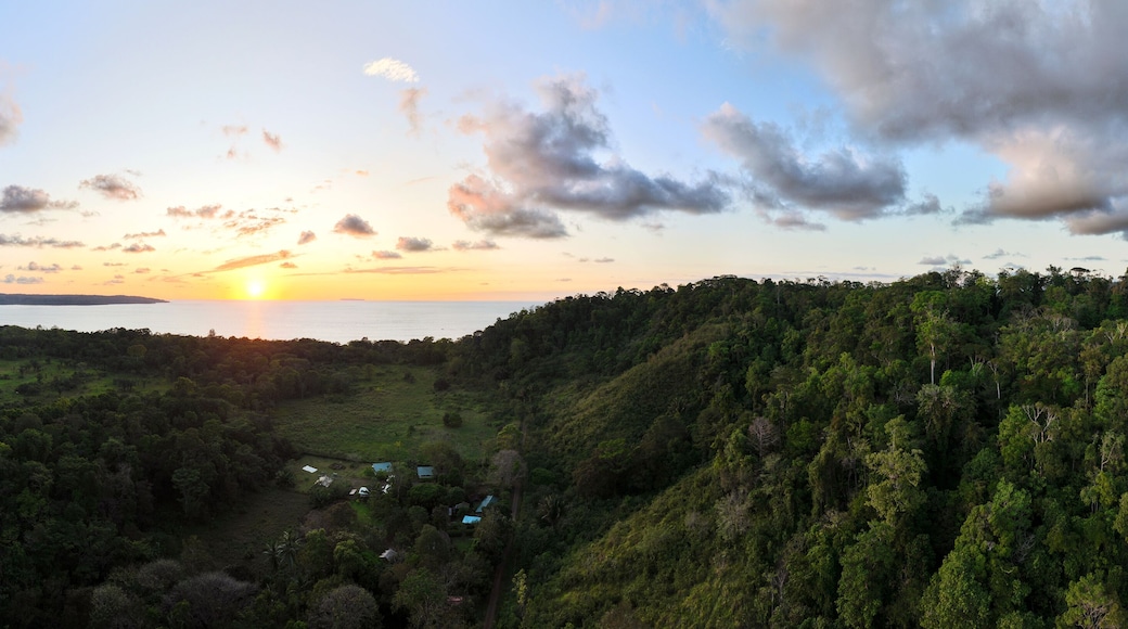 Wide aerial panorama of sunset over rural Costa Rica forest looking out towards the ocean and the setting sun. Drone photo taken near Drake Bay.