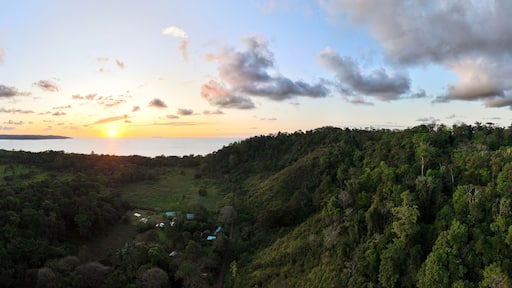 Wide aerial panorama of sunset over rural Costa Rica forest looking out towards the ocean and the setting sun. Drone photo taken near Drake Bay.