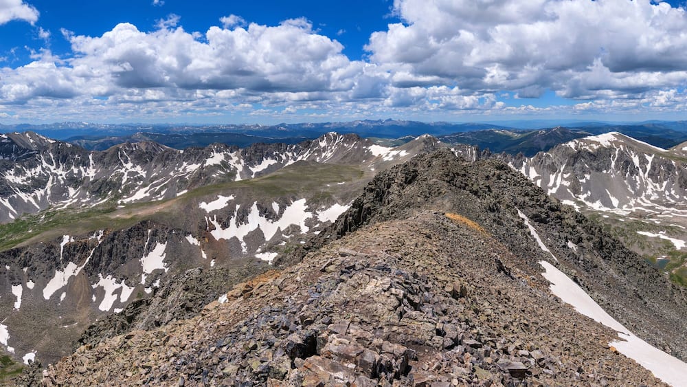 Summer Summit View - A panorama of white clouds rolling over rugged high mountain peaks at Continental Divide, as seen at summit of Quandary Peak looking towards west, on a sunny Summer day. CO, USA.