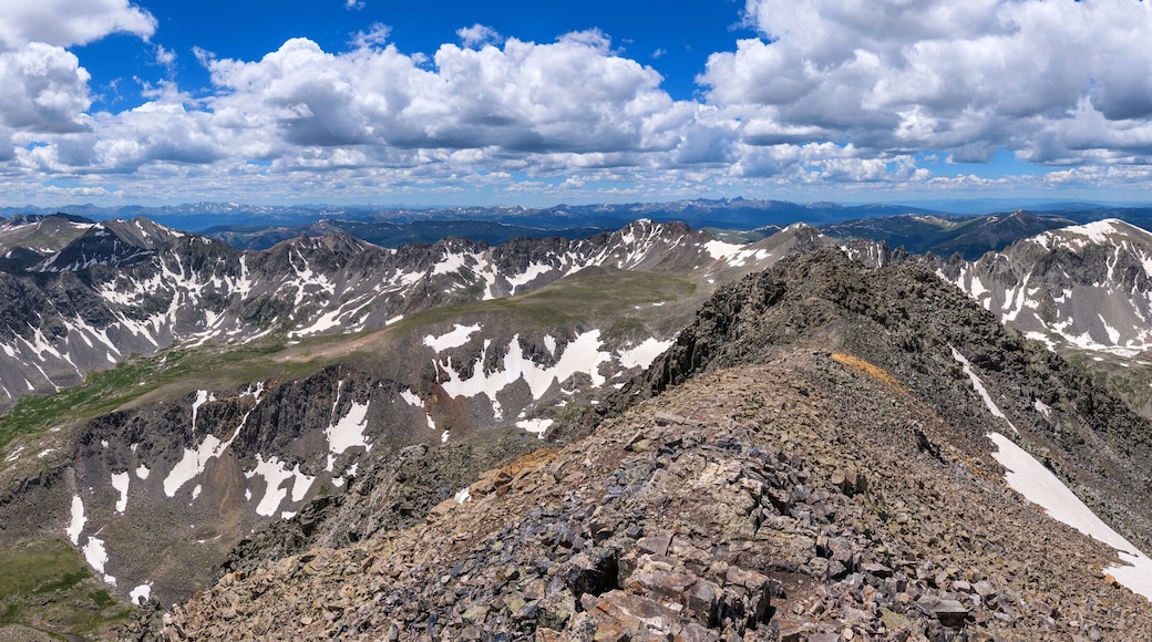 Summer Summit View - A panorama of white clouds rolling over rugged high mountain peaks at Continental Divide, as seen at summit of Quandary Peak looking towards west, on a sunny Summer day. CO, USA.