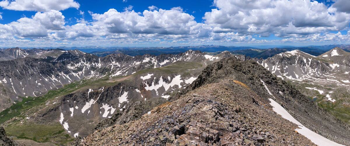 A mountain ridge with snow patches and a clear sky.