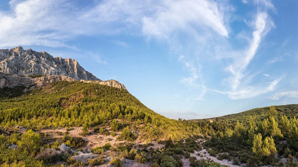 A mountainous landscape with dense forests and a prominent rocky peak.