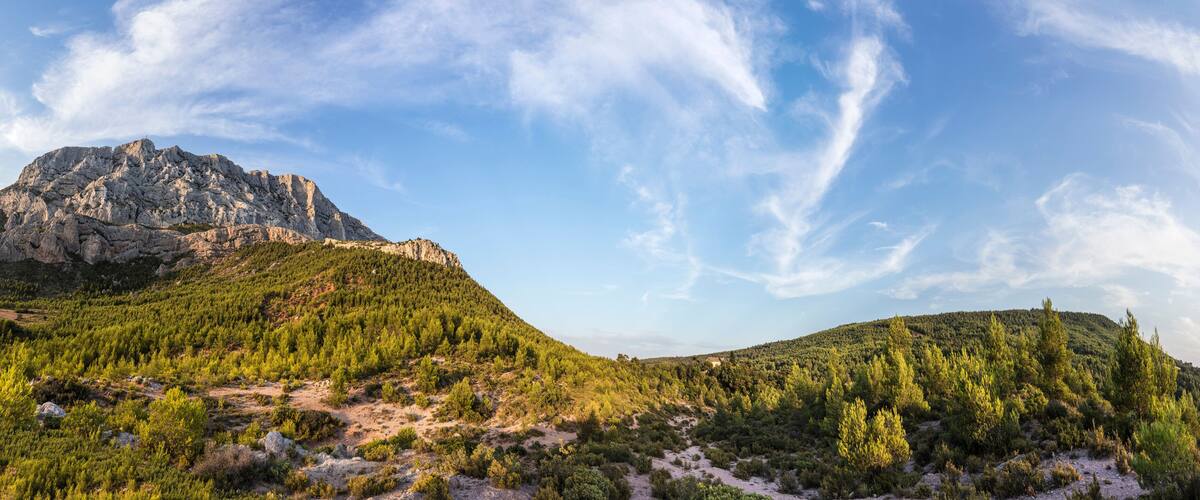 A mountainous landscape with dense forests and a prominent rocky peak.