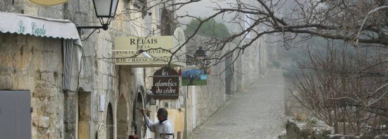 Rua de paralelepípedos com um café e uma placa com 'La Cigale'.