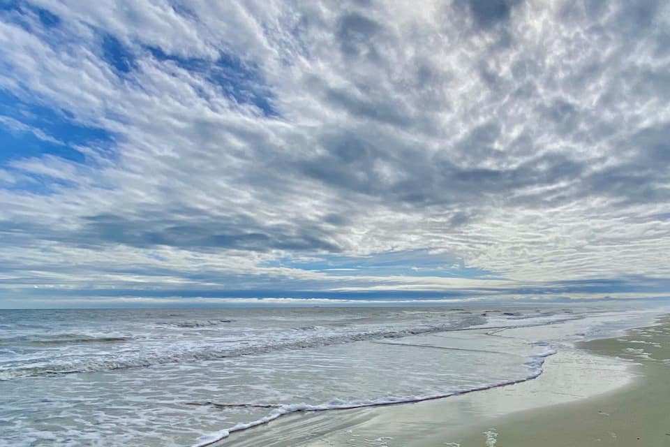 A beach with waves and a cloudy sky.
