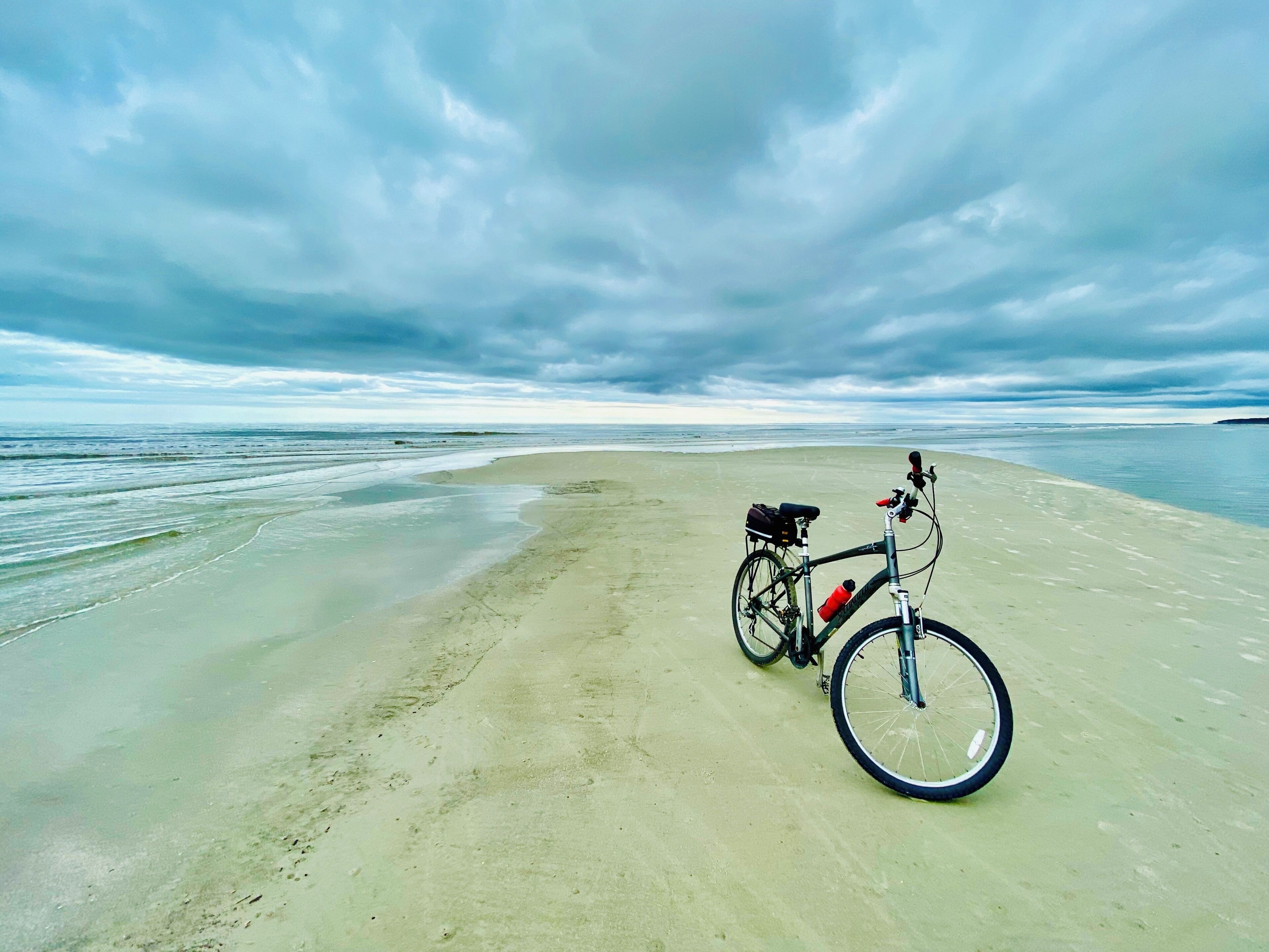 A bicycle on a sandy beach with the ocean in the background.