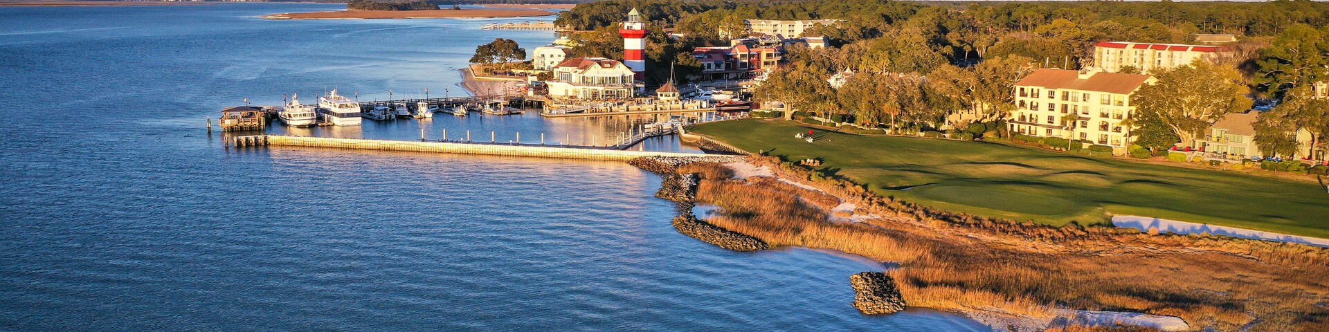 A coastal town with a lighthouse, marina, and golf course.