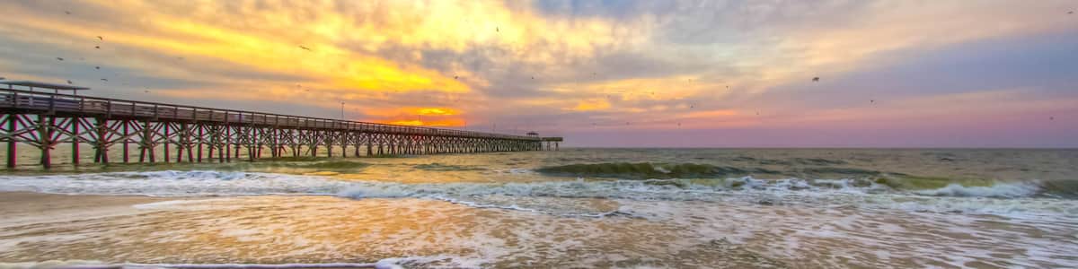 Dramatic sunrise beach with fishing pier in Myrtle Beach, South Carolina.