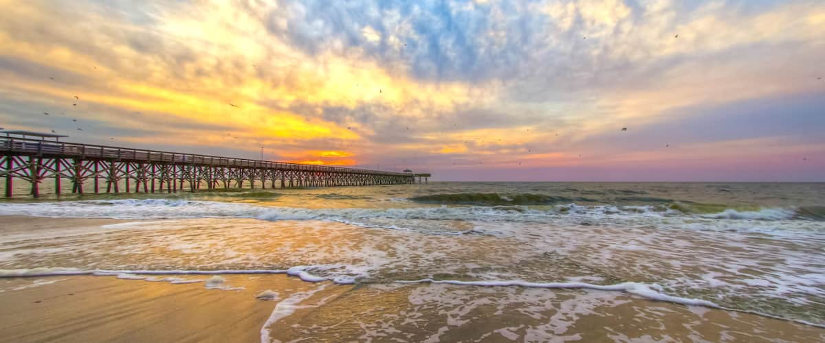 Dramatic sunrise beach with fishing pier in Myrtle Beach, South Carolina.