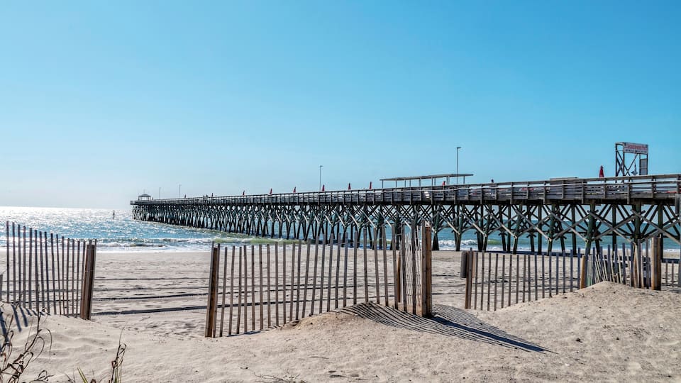 A wooden pier extending into the ocean with a clear sky above.