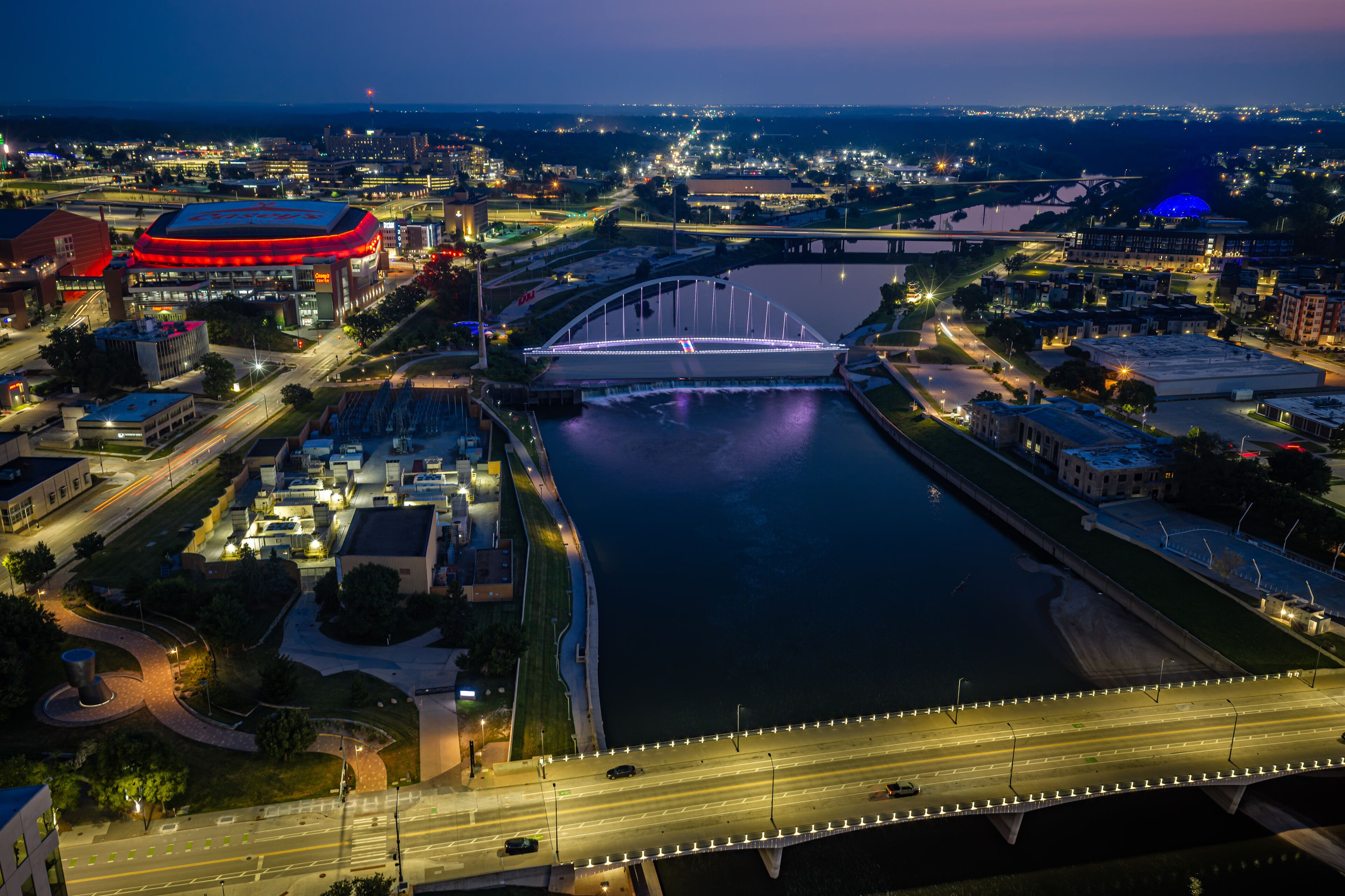 A cityscape at night with a prominent bridge, illuminated buildings, and a river.