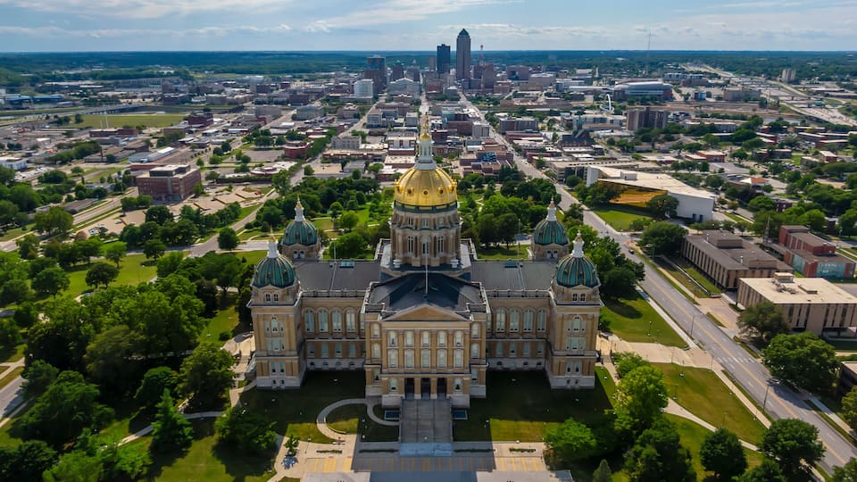 An aerial view of a city with a prominent building featuring a golden dome and green-topped towers.