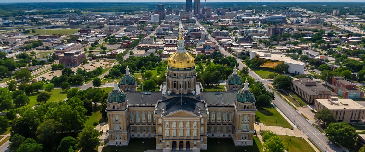 An aerial view of a city with a prominent building featuring a golden dome and green-topped towers.