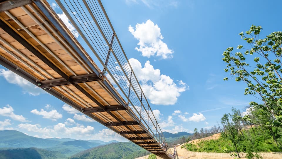 A suspension bridge with a clear view of the surrounding mountainous landscape.