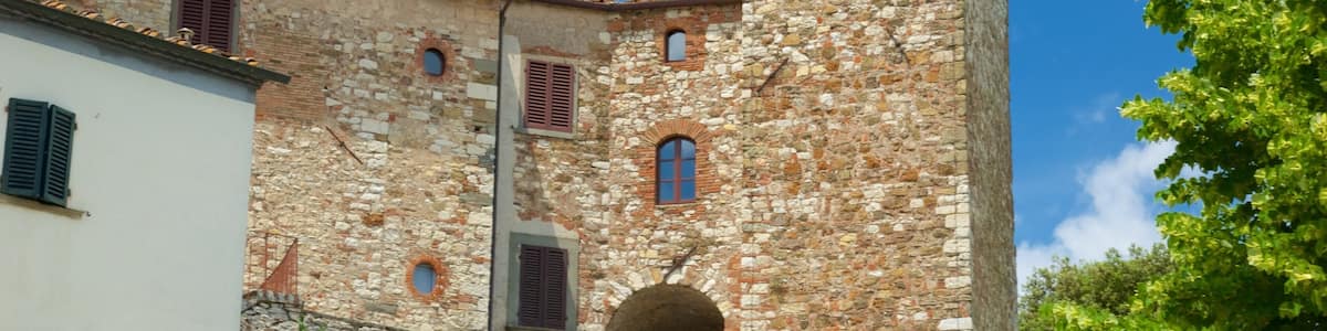 A stone building with a tower, arched windows, and a red-tiled roof.