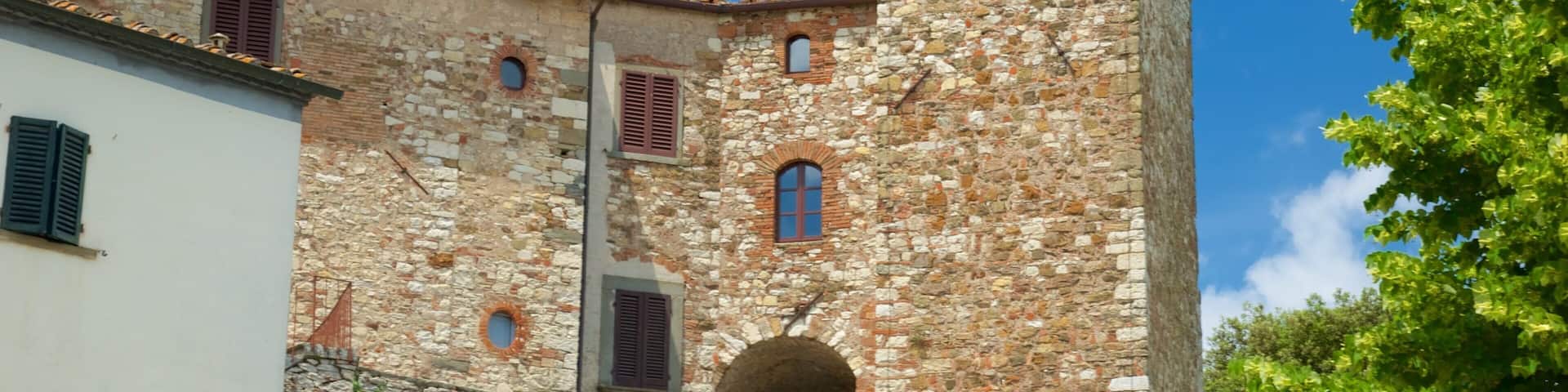 A stone building with a tower, arched windows, and a red-tiled roof.