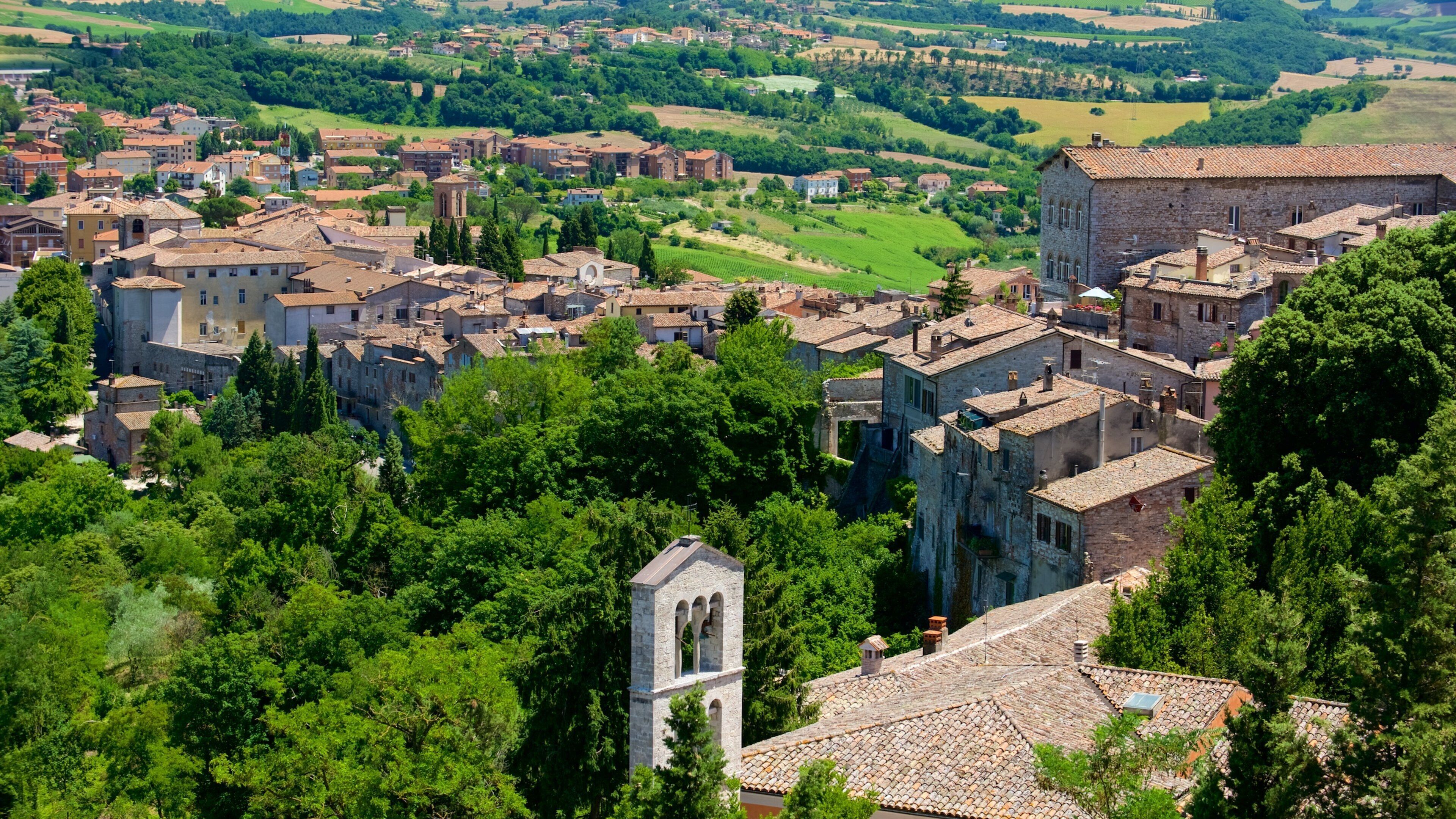 A historic town with medieval architecture, surrounded by lush greenery and rolling hills.