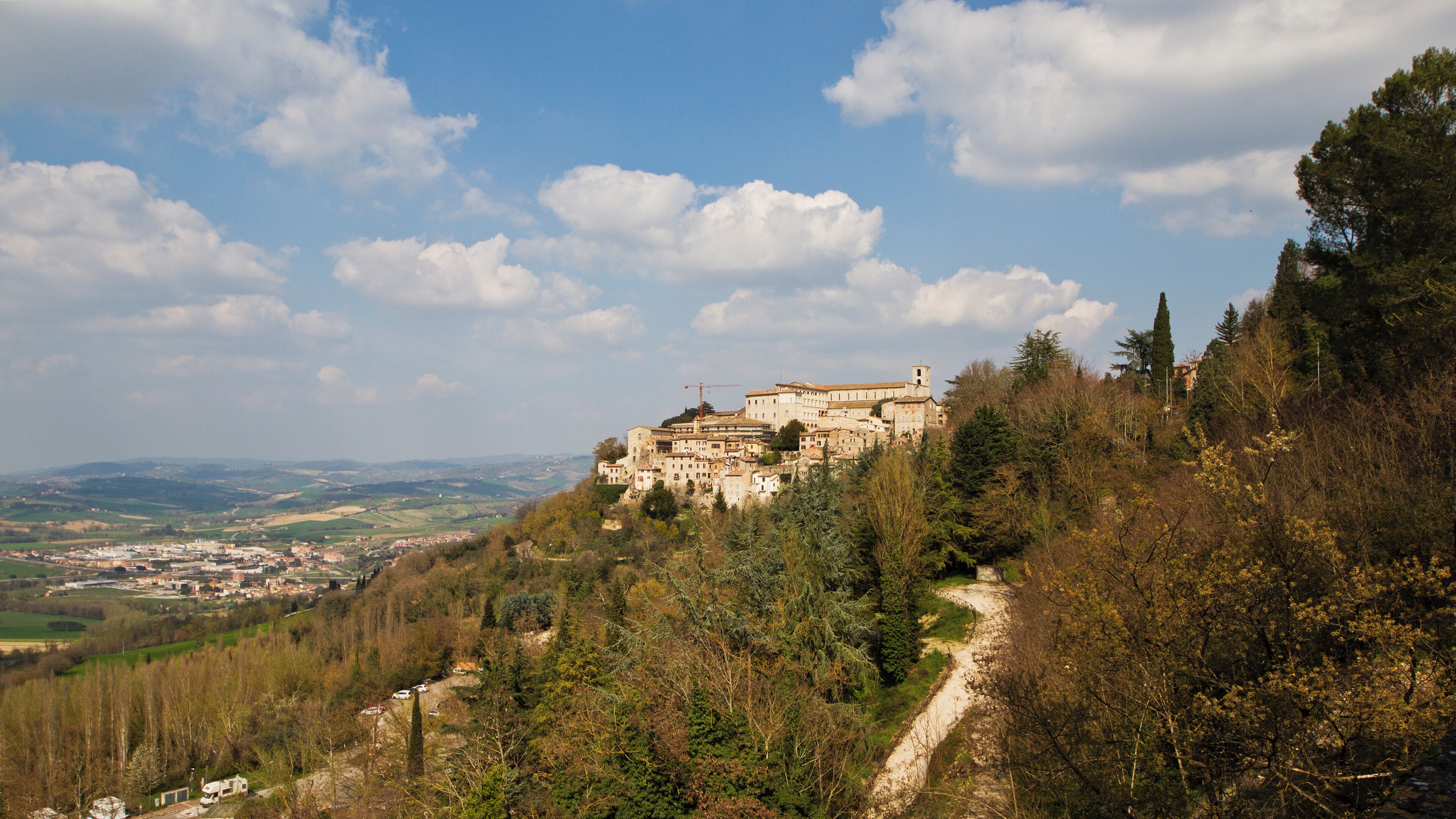 A historic hilltop town with a prominent church, surrounded by dense forest and rolling hills.