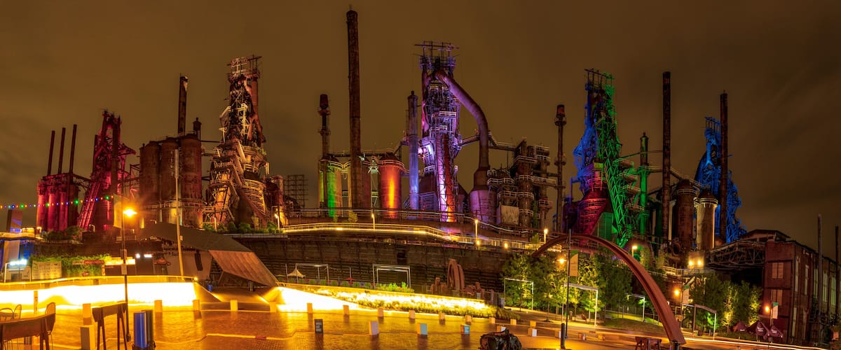 A nighttime industrial complex with illuminated structures and a large central building.