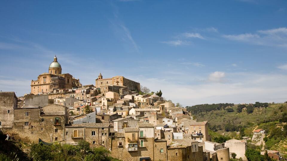 A historic town with a prominent church featuring a dome, surrounded by densely packed buildings on a hillside.