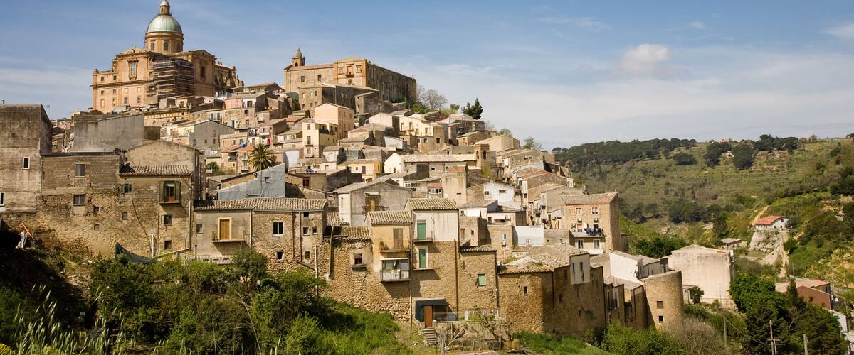 A historic town with a prominent church featuring a dome, surrounded by densely packed buildings on a hillside.