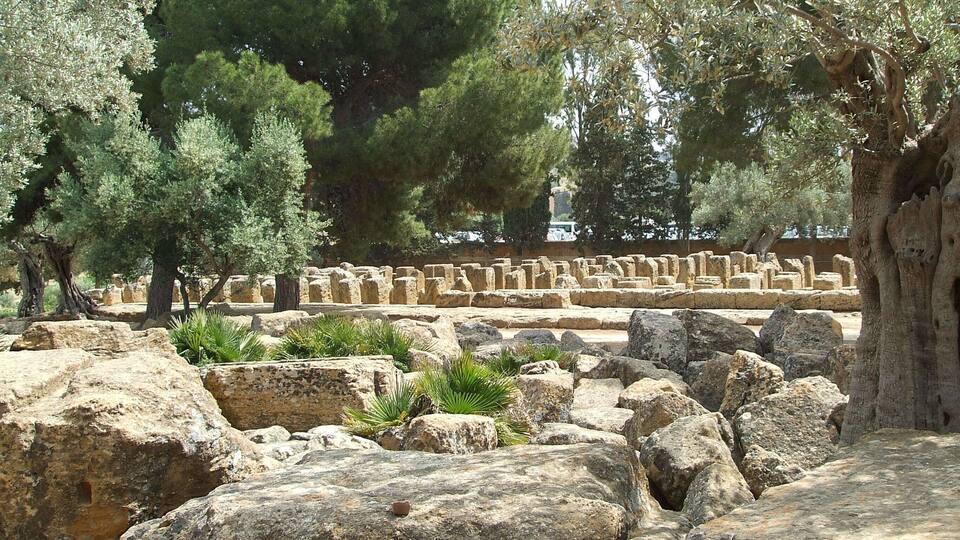 Ancient ruins with stone blocks and trees.