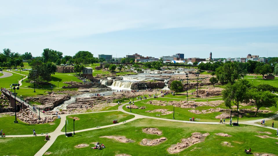 A park with a waterfall, walking paths, and a bridge.