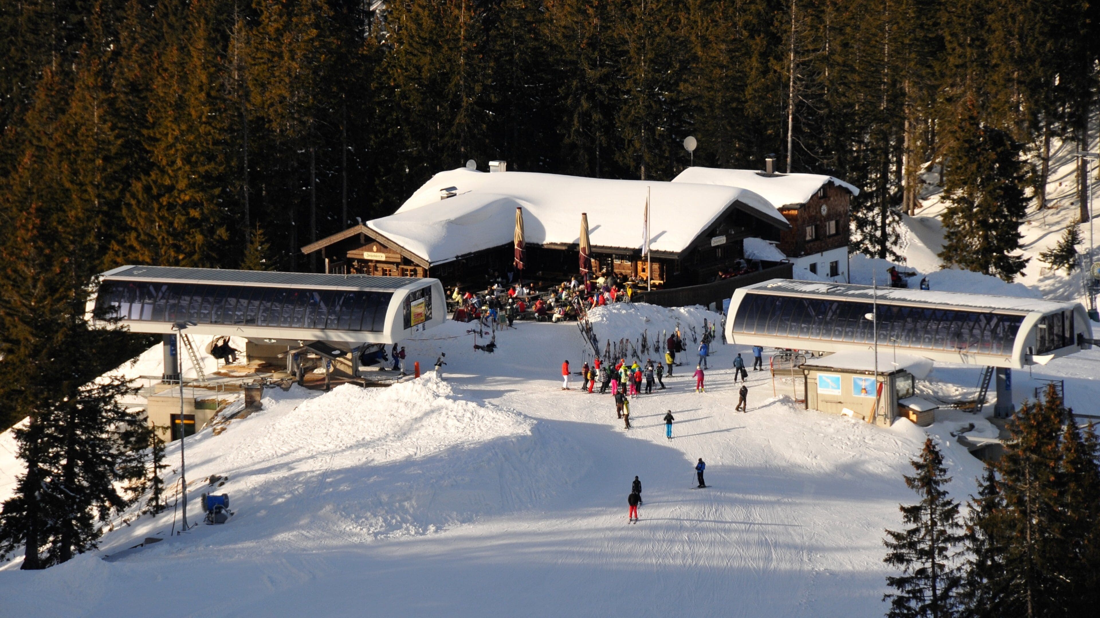 Estación de esquí con telesilla, pistas cubiertas de nieve y un edificio de techo inclinado.