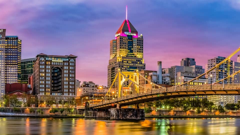 A city skyline with illuminated buildings and a prominent bridge.