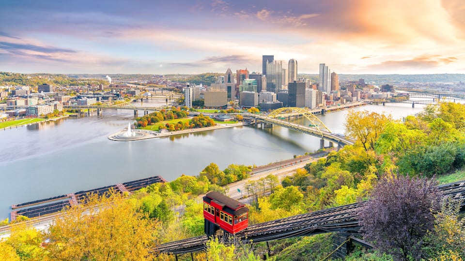 A cityscape with a river, bridges, and a red tram.