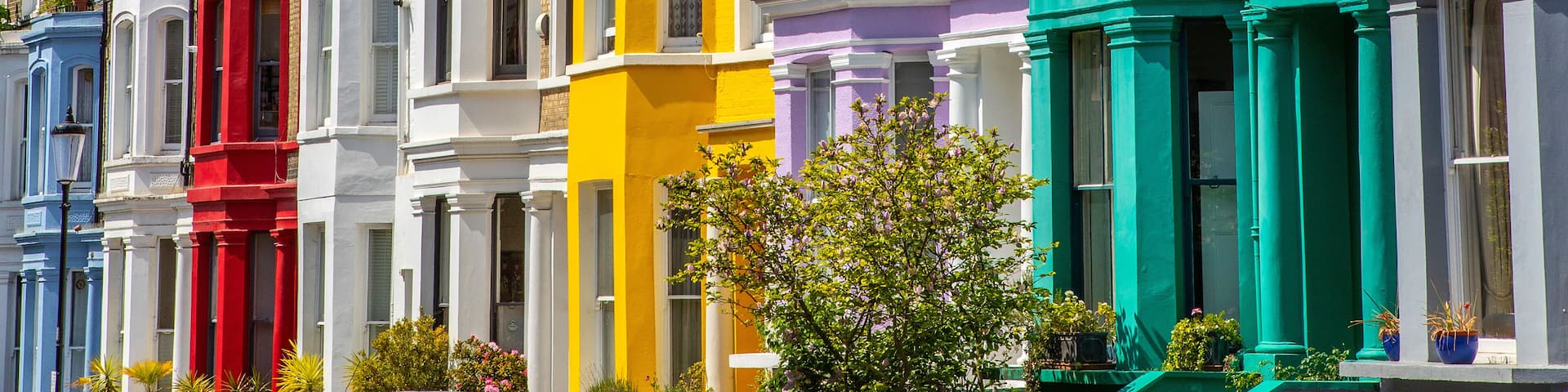 A row of colorful Victorian townhouses with distinct pastel hues and classic architectural details.
